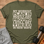 Olive green t-shirt with white text: "MY WORKOUT PLAN IS MOSTLY JUST PROVING I STILL GET TIRED IN NEW WAYS."