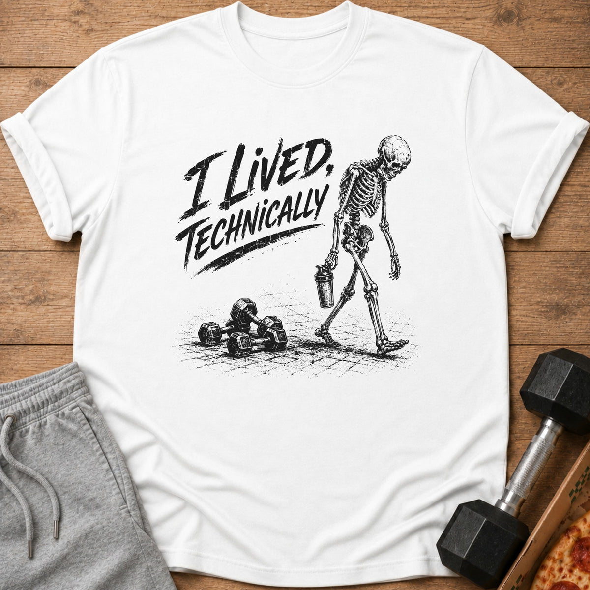 White t-shirt with "I Lived, Technically" text and skeleton walking past dumbbells.