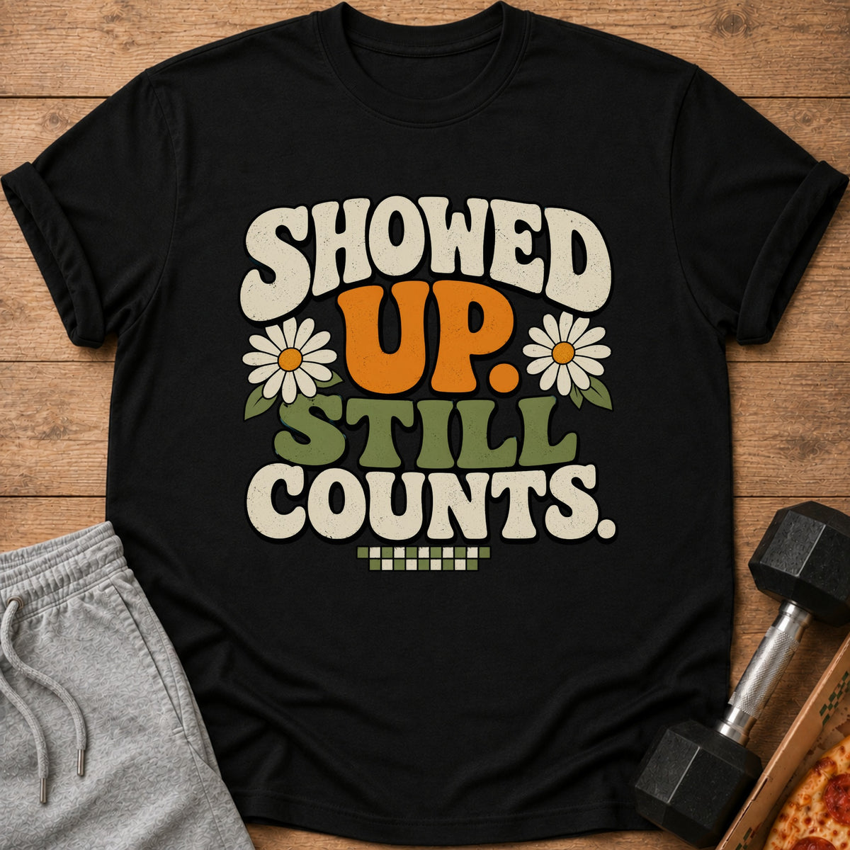 Black t-shirt with "SHOWED UP. STILL COUNTS." text and daisy graphics.