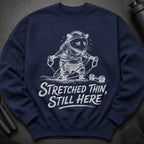 Navy sweatshirt with a graphic of a possum exercising and text reading "Stretched Thin, Still Here".