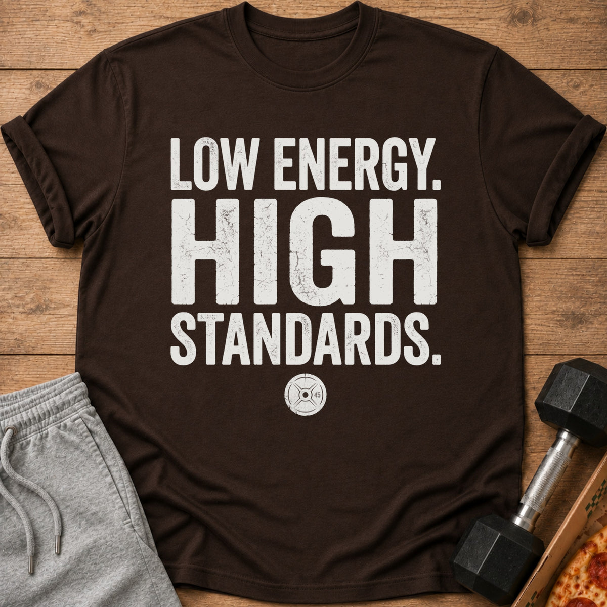 Brown t-shirt with white text "LOW ENERGY. HIGH STANDARDS." and weight plate graphic.