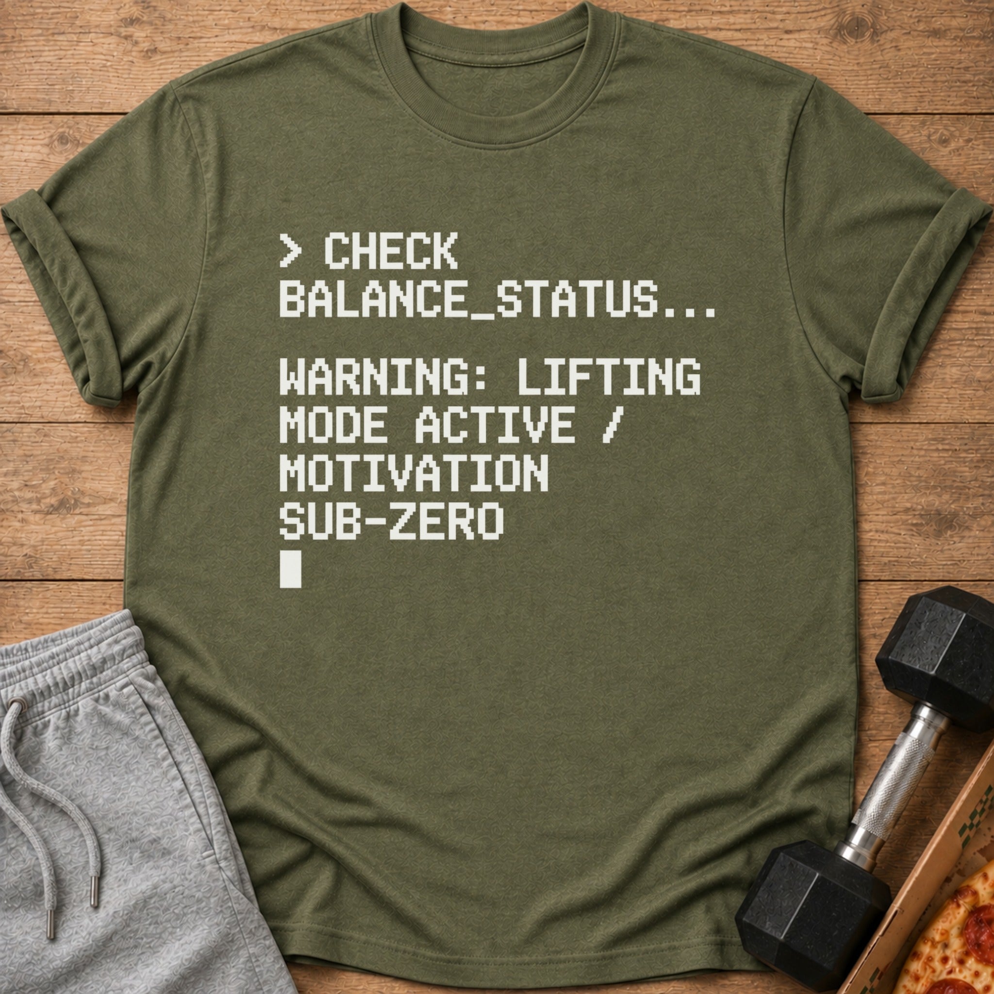Olive green t-shirt with white pixelated text reading "CHECK BALANCE_STATUS..."