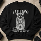 Black sweatshirt with white print "Lifting Against My Nature" and a possum holding a kettlebell.