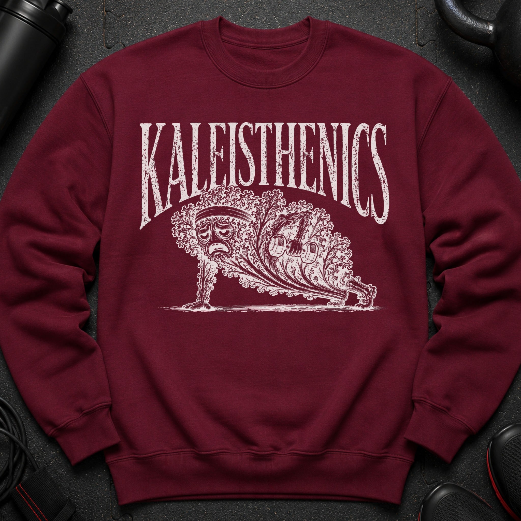 Maroon sweatshirt with white "KALEISTHENICS" text and a sad, leafy figure doing a plank with a dumbbell.