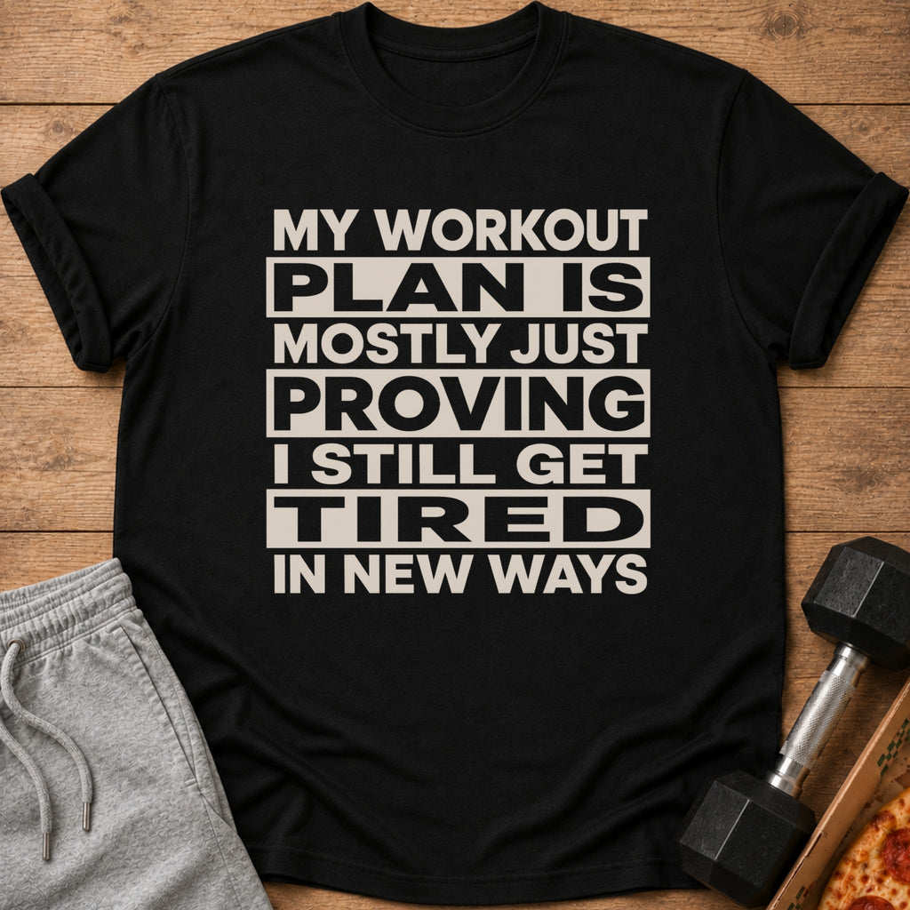 Black t-shirt with text: "MY WORKOUT PLAN IS MOSTLY JUST PROVING I STILL GET TIRED IN NEW WAYS."