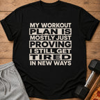 Black t-shirt with text: "MY WORKOUT PLAN IS MOSTLY JUST PROVING I STILL GET TIRED IN NEW WAYS."