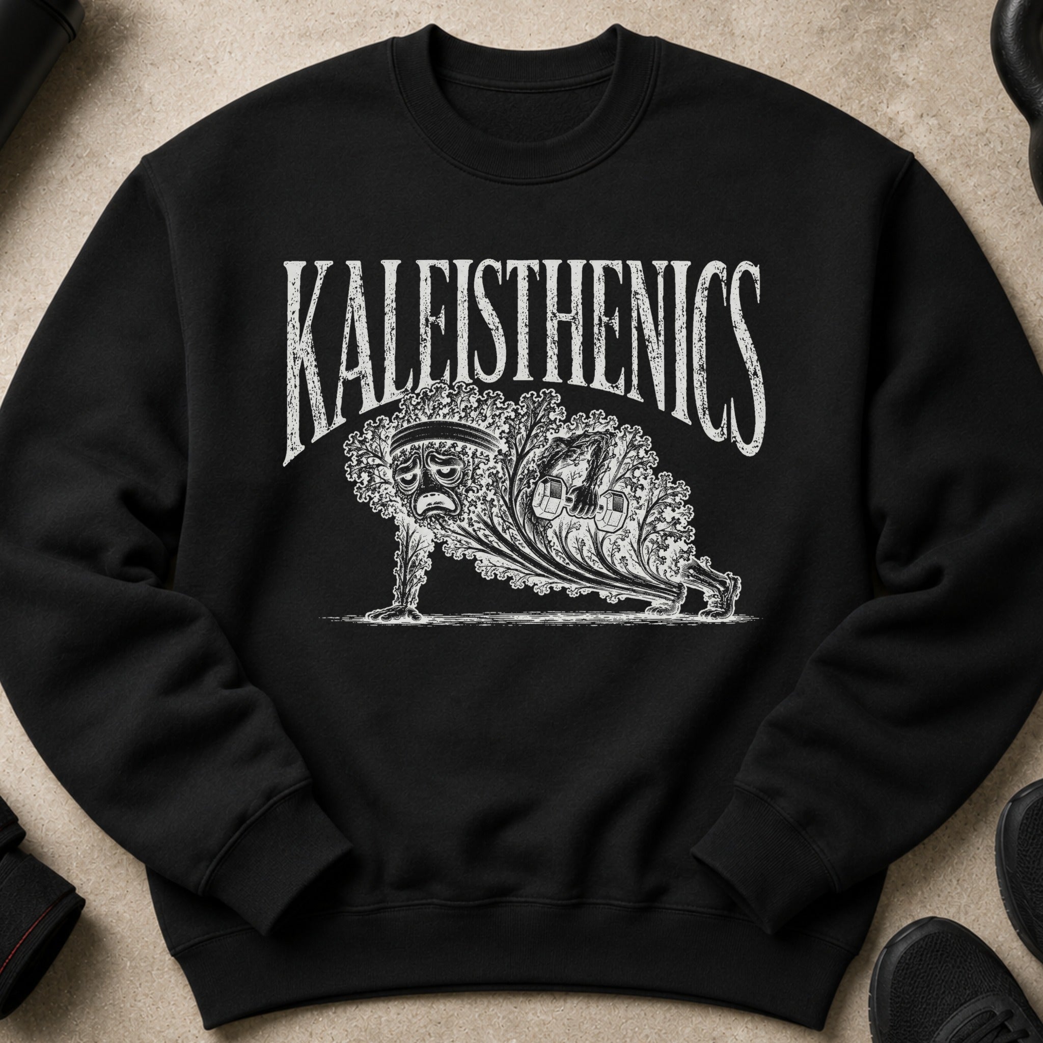 Black crewneck sweatshirt with white graphic of "KALEISTHENICS" and sad kale doing a plank with dumbbells.