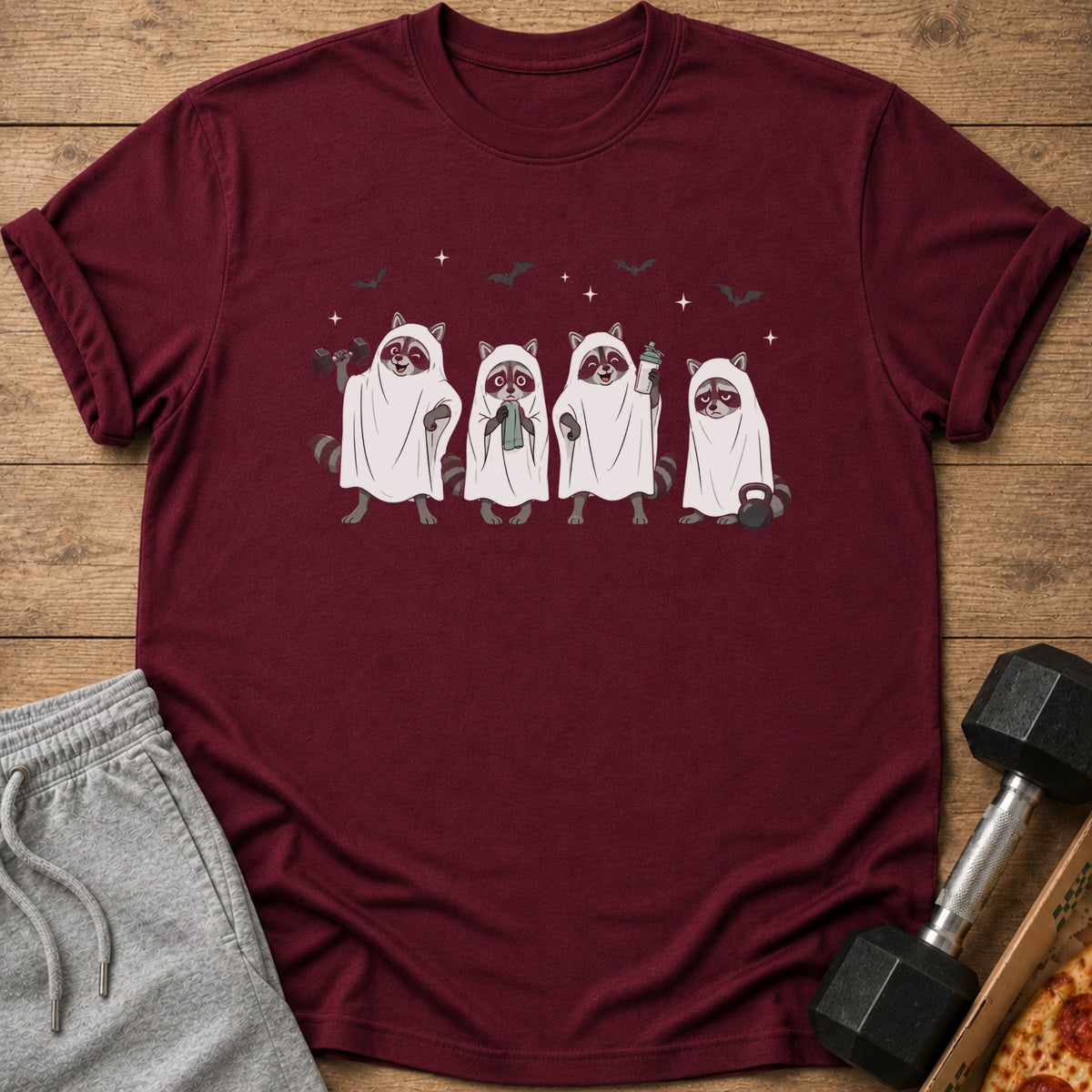 Four raccoons in ghost costumes holding workout items and a dumbbell next to a pizza.
