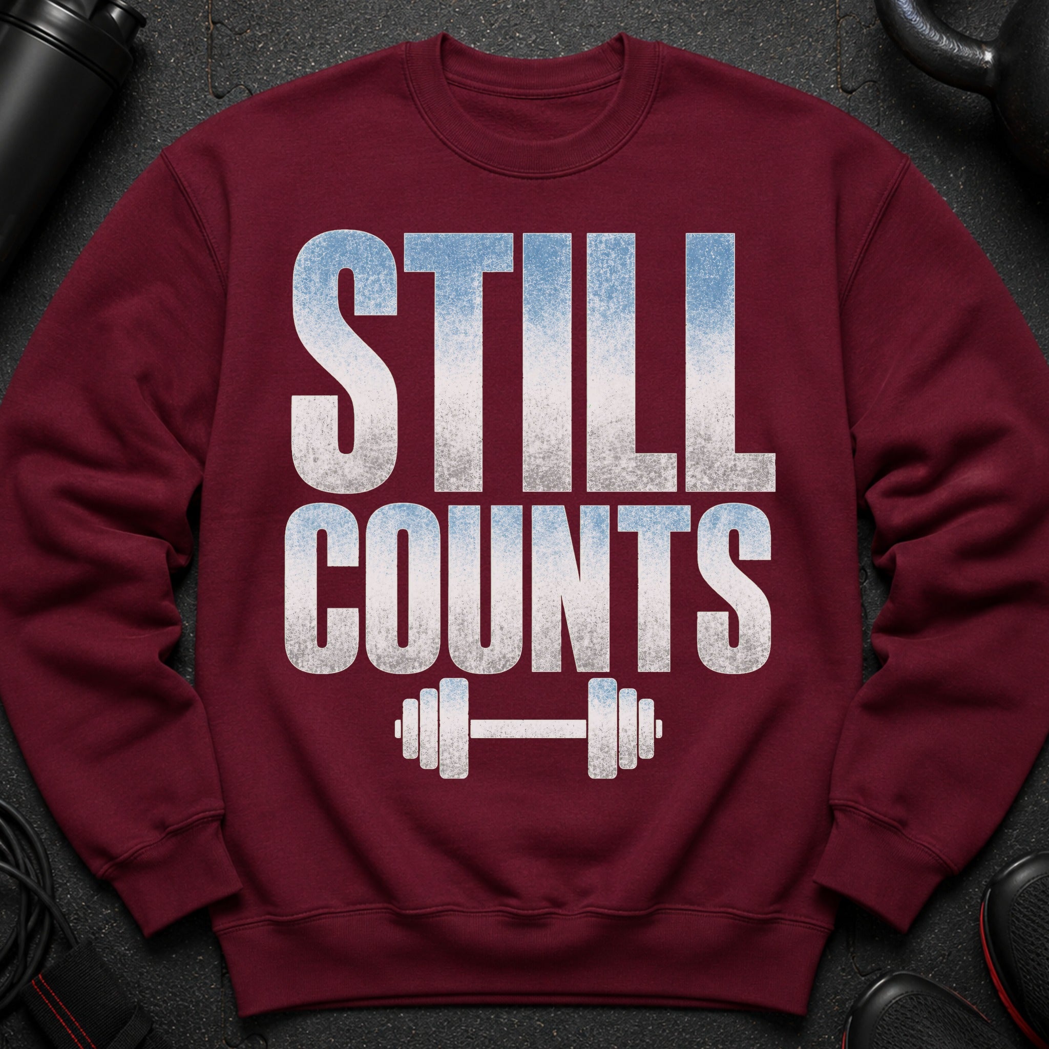 Maroon sweatshirt with "STILL COUNTS" text and dumbbell graphic.