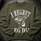 Green sweatshirt with white text "I REGRET" and a flamingo holding a kettlebell, "LEG DAY" below
