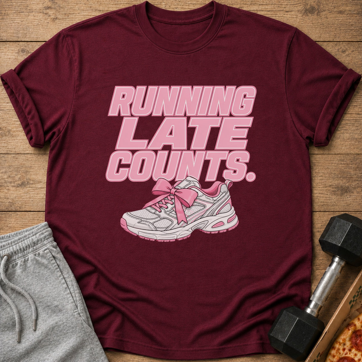 Maroon t-shirt with pink text "RUNNING LATE COUNTS." and a pink bow on a white sneaker.