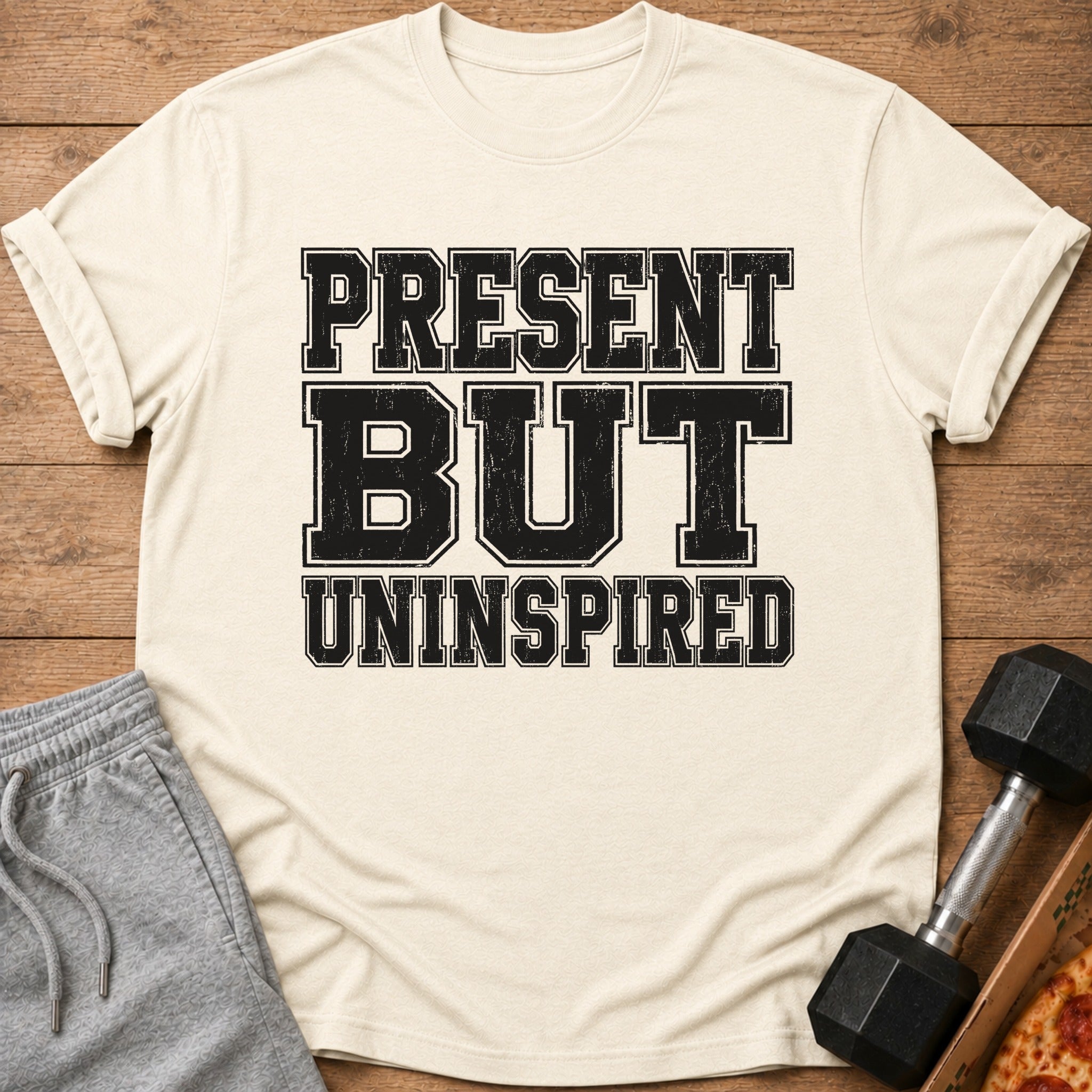 Cream t-shirt with black distressed text reading "PRESENT BUT UNINSPIRED".