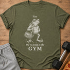Green t-shirt with a graphic of a frog in a hoodie carrying a gym bag with text.
