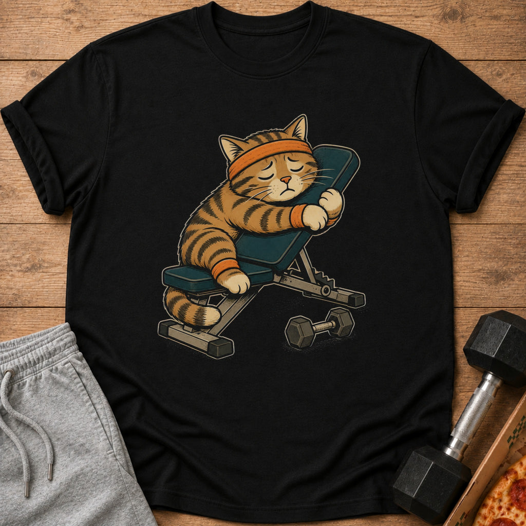 Tiger cat wearing headband and wristbands rests on weight bench with dumbbell.