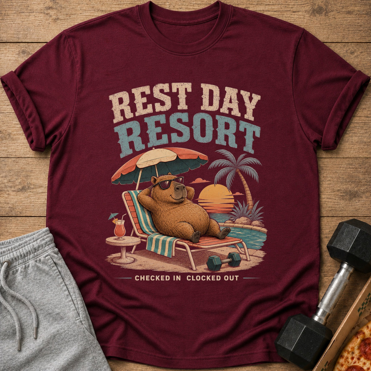 Maroon t-shirt with "Rest Day Resort" graphic of a capybara relaxing by a pool.