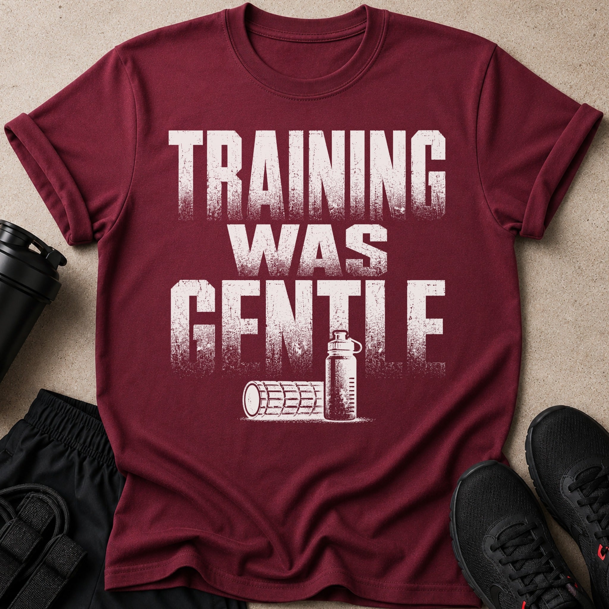 Maroon t-shirt with "TRAINING WAS GENTE" text, workout bottle, and foam roller.