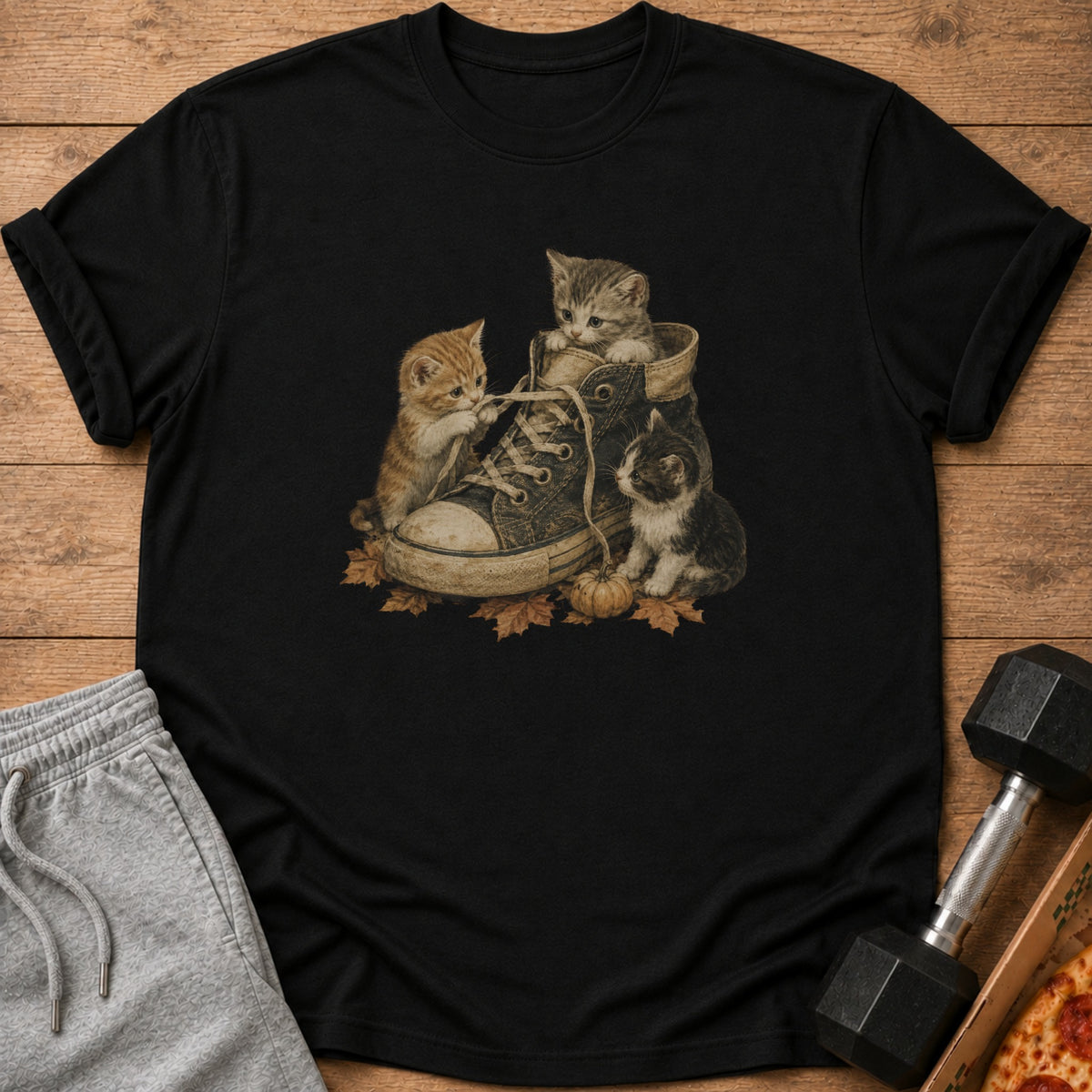 Three kittens play with the laces of a worn sneaker surrounded by autumn leaves.