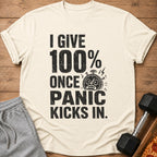 Cream t-shirt with distressed text "I GIVE 100% ONCE PANIC KICKS IN" and a stopwatch graphic.