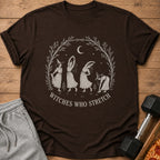 Brown t-shirt with "Witches Who Stretch" graphic of witches doing yoga poses.