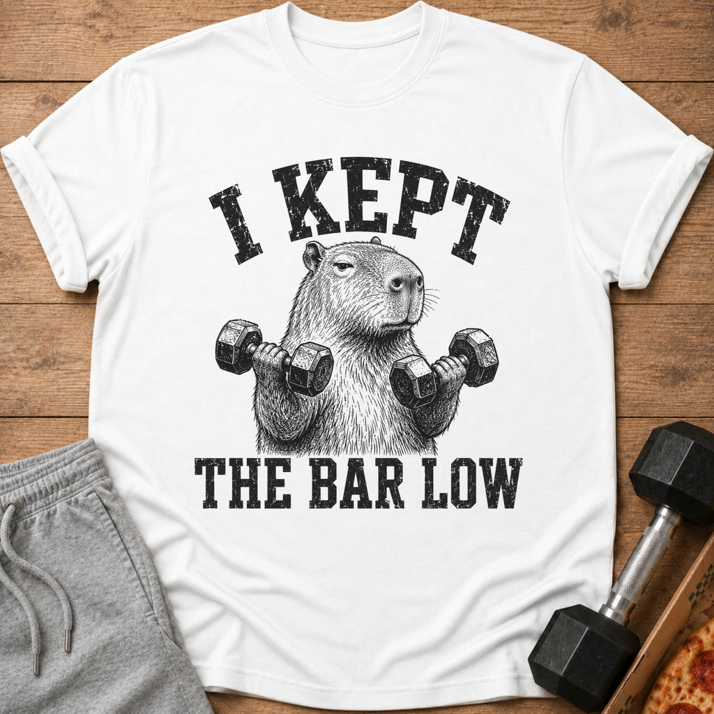 White t-shirt with a capybara holding dumbbells and text "I KEPT THE BAR LOW".