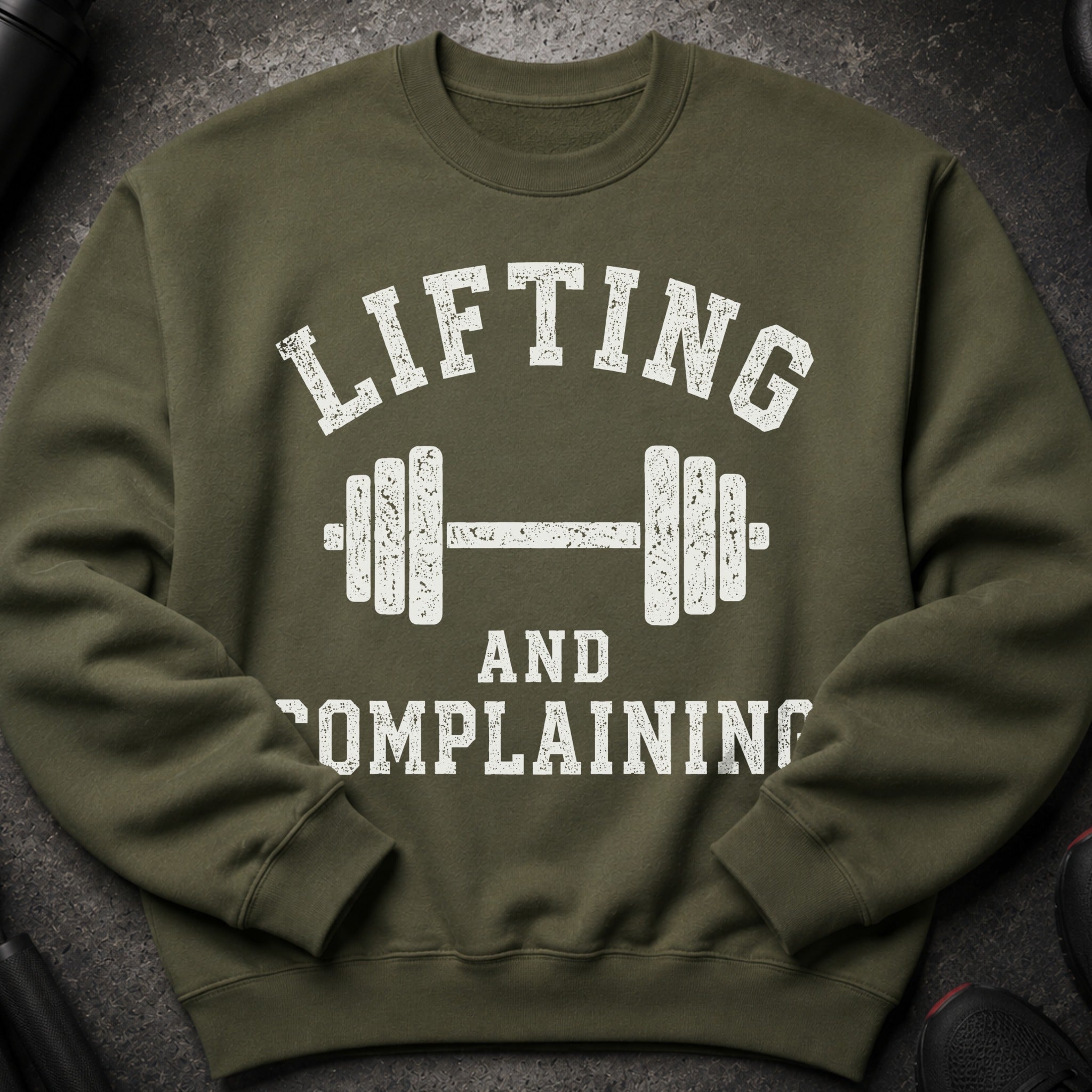Olive green sweatshirt with white distressed text "LIFTING AND COMPLAINING" and dumbbell graphic.