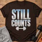 Brown t-shirt with distressed "STILL COUNTS" text and barbell graphic.