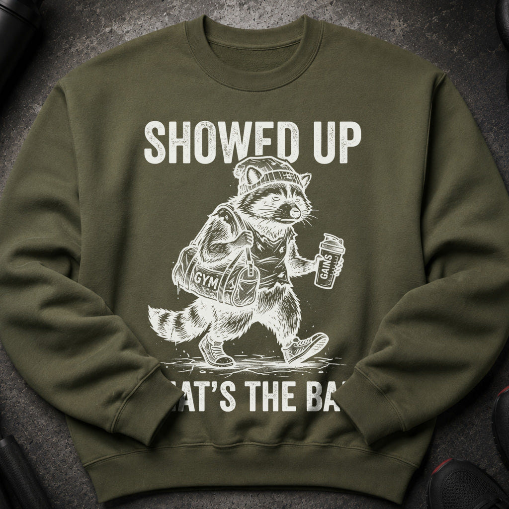 Green sweatshirt with graphic of raccoon at gym holding bag and drink.