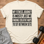 Cream t-shirt with text "My fitness journey is mostly just me finding creative ways to sit between sets."
