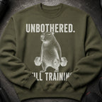 Olive green sweatshirt with "UNBOTHERED. STILL TRAINING." and a capybara lifting dumbbells.