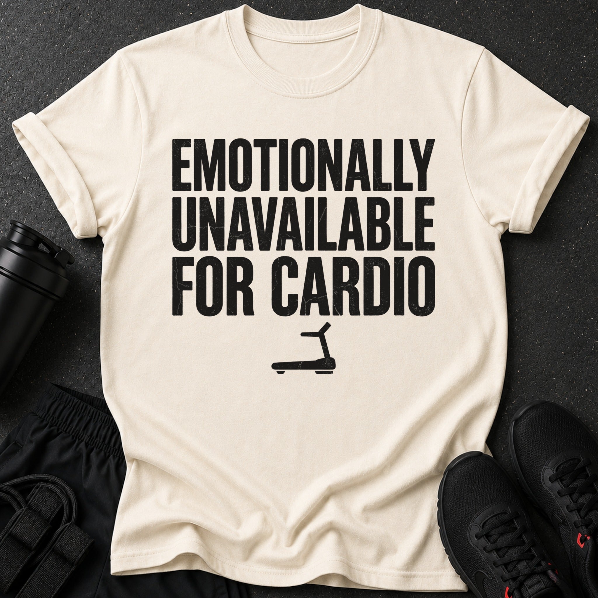 Light cream t-shirt with black text saying "EMOTIONALLY UNAVAILABLE FOR CARDIO" and a treadmill graphic.