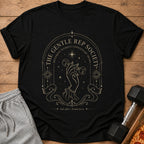 Black t-shirt with gold graphic: hand holding dumbbell, text: The Gentle Rep Society, Movement Without Unnecessary Drama.