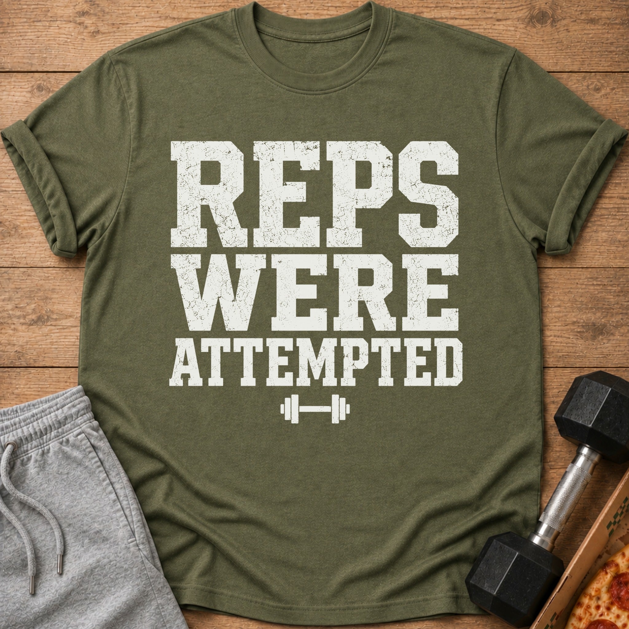 Green t-shirt with white distressed text "REPS WERE ATTEMPTED" and a dumbbell graphic.