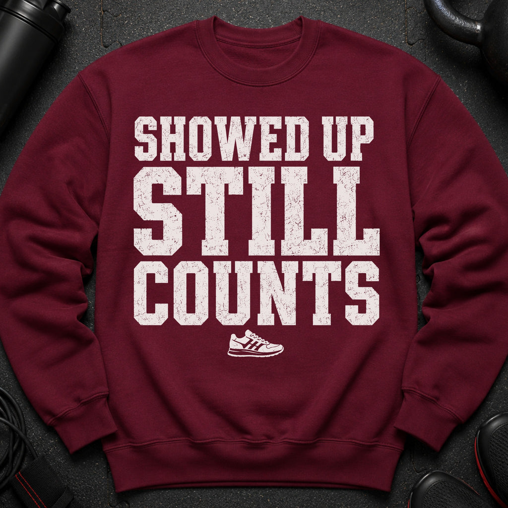 Maroon sweatshirt with distressed white text reading "SHOWED UP STILL COUNTS" and a sneaker graphic.