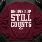 Maroon sweatshirt with distressed white text reading "SHOWED UP STILL COUNTS" and a sneaker graphic.