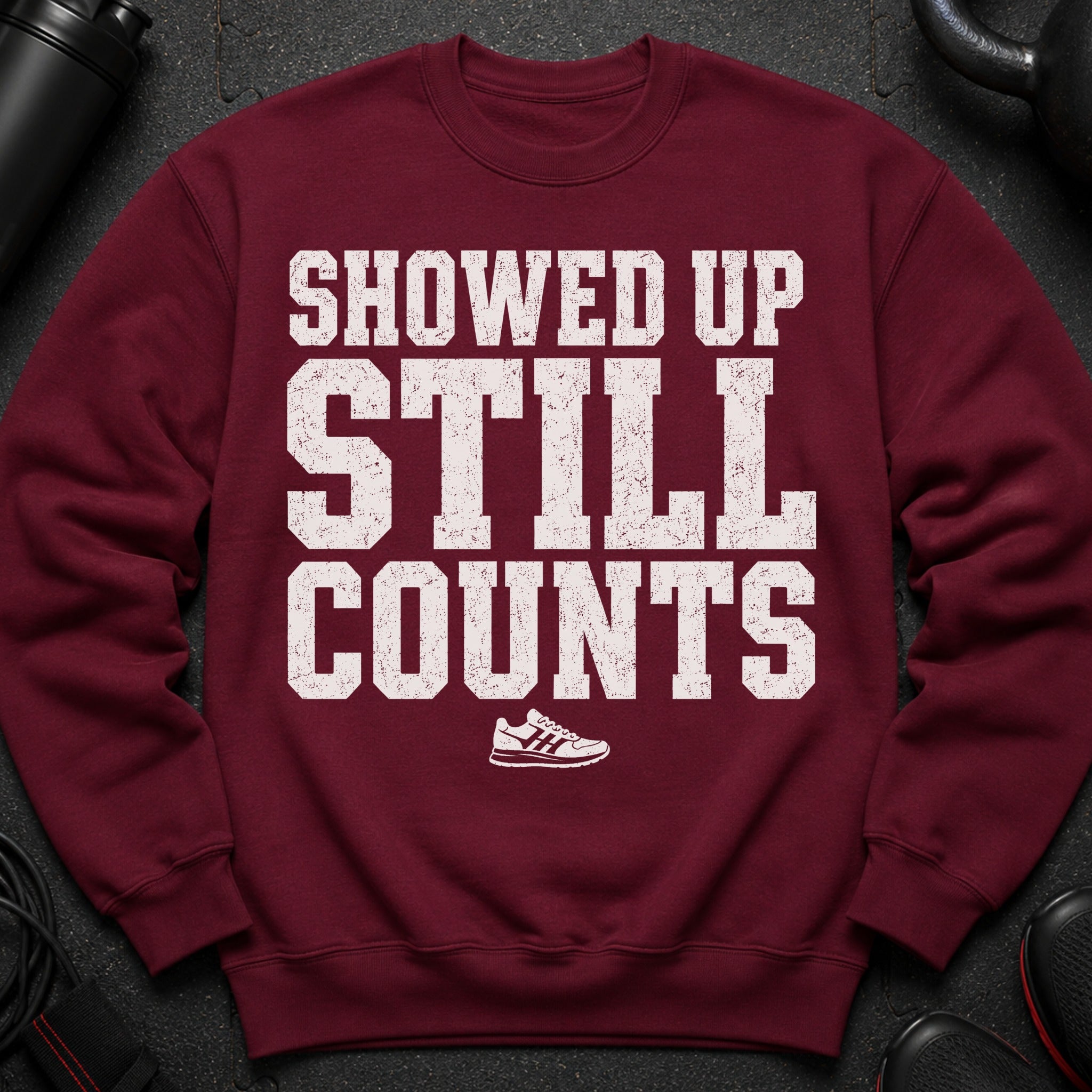 Maroon sweatshirt with distressed white text reading "SHOWED UP STILL COUNTS" and a sneaker graphic.