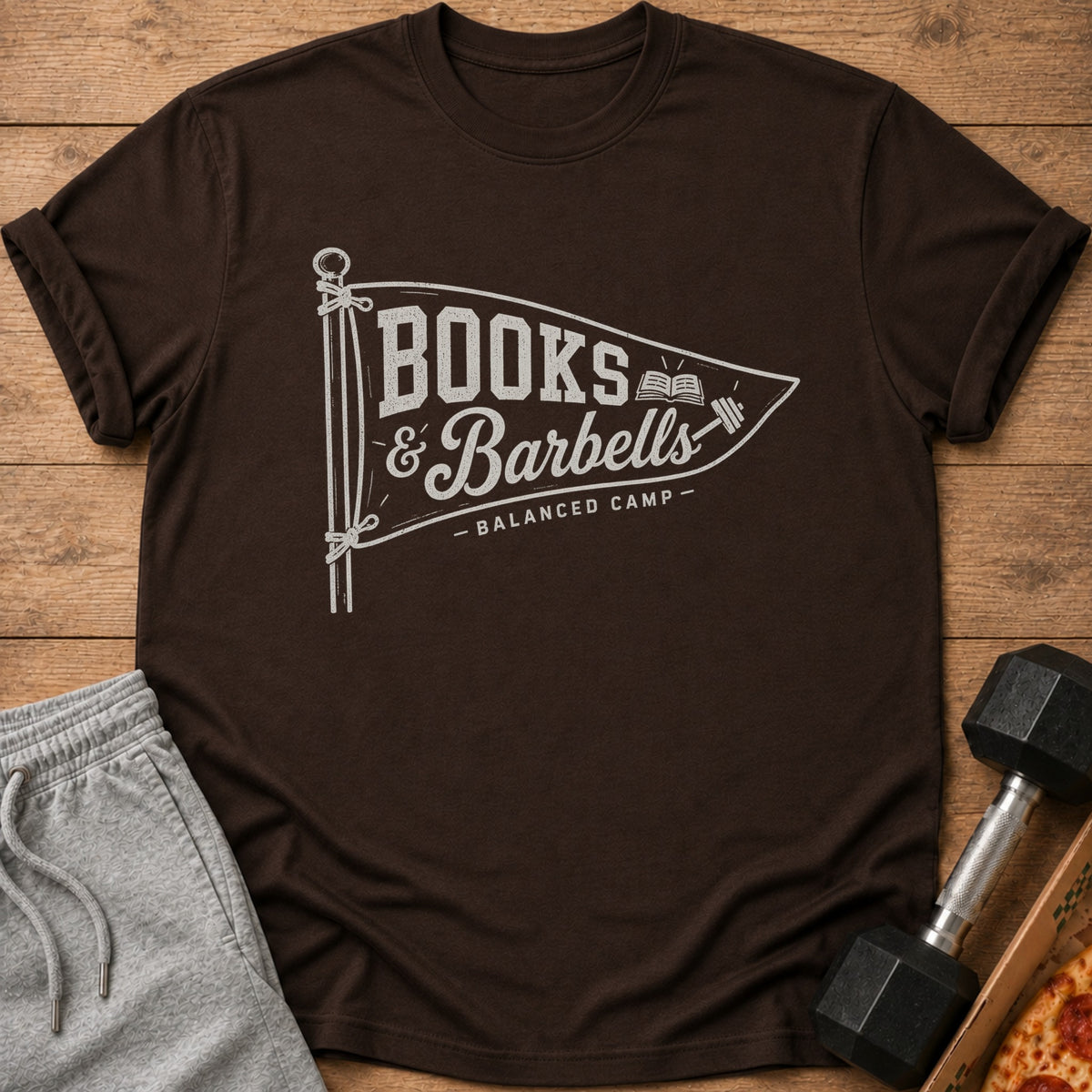 Brown t-shirt with "BOOKS & Barbells - BALANCED CAMP -" graphic on a pennant.