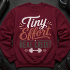 Maroon sweatshirt with text "Tiny Effort, Real Credit" and dumbbell graphic.