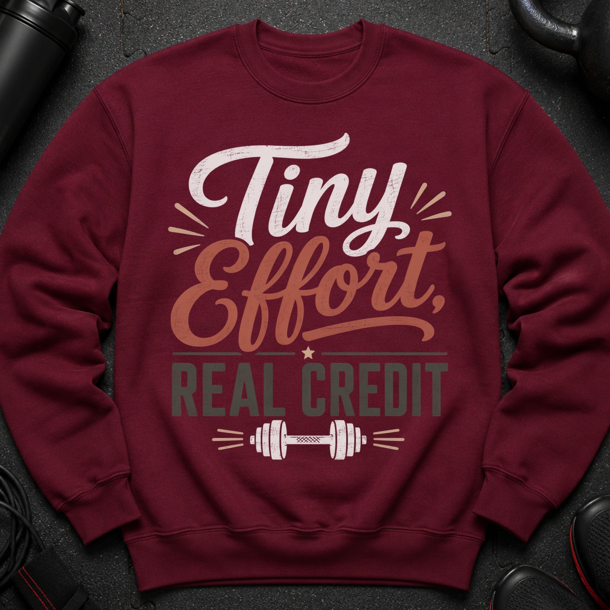 Maroon sweatshirt with text "Tiny Effort, Real Credit" and dumbbell graphic.