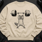 Beige sweatshirt with a black ink drawing of a raccoon lifting a barbell.