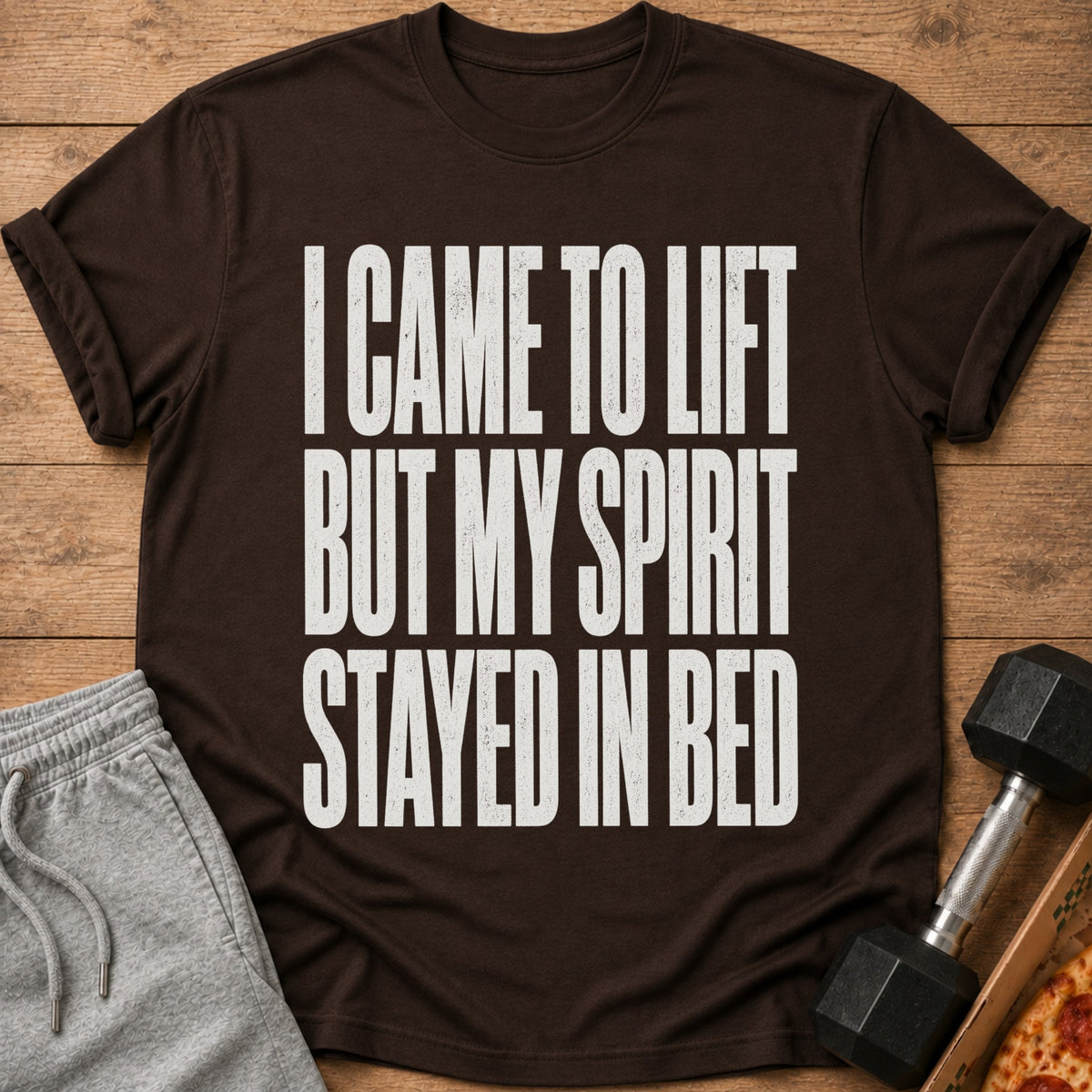 Brown t-shirt with white text: "I CAME TO LIFT BUT MY SPIRIT STAYED IN BED".