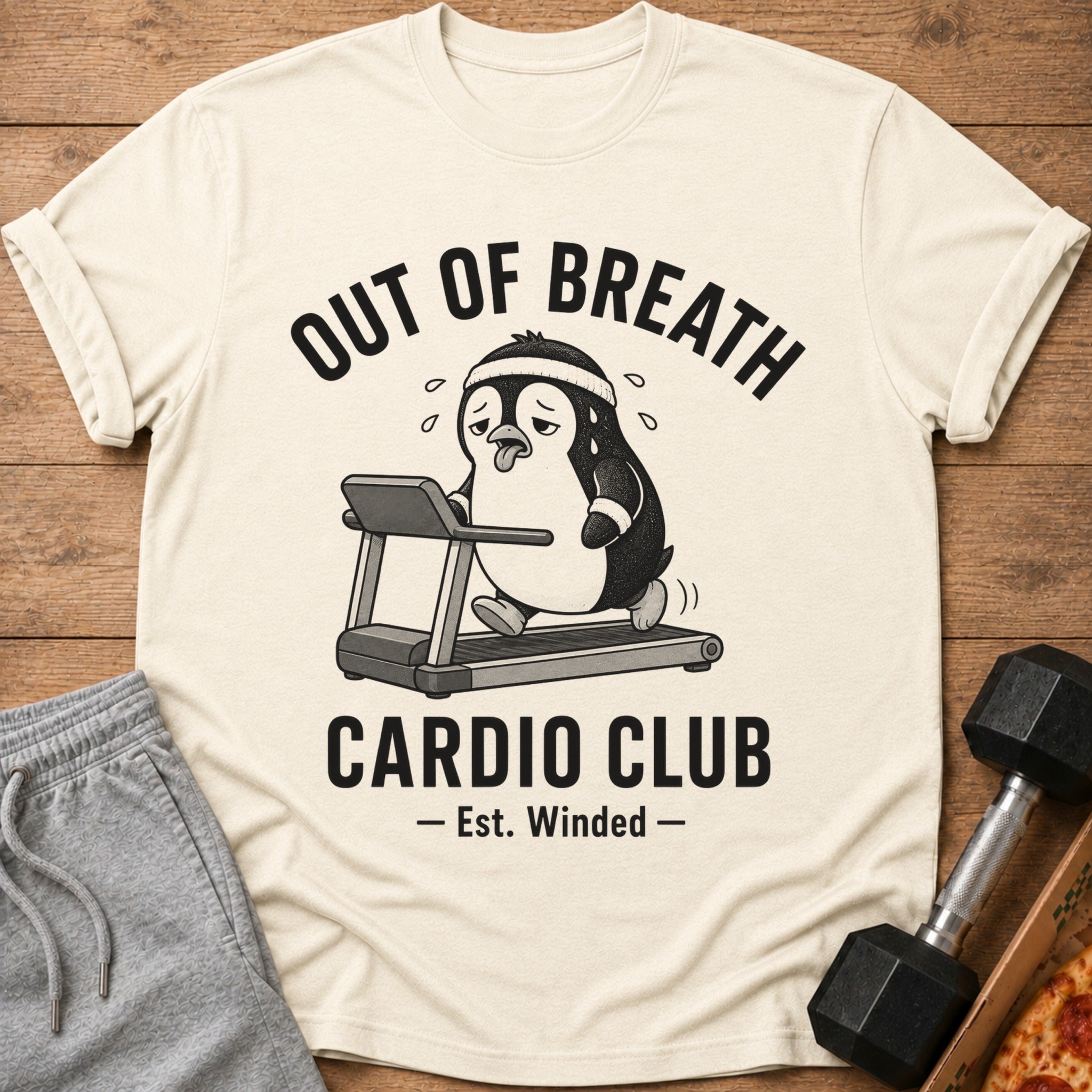 Cream t-shirt with cartoon penguin on treadmill and text "OUT OF BREATH CARDIO CLUB - Est. Winded -".