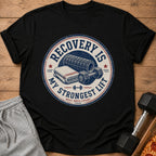 Black t-shirt with distressed graphic: "Recovery Is My Strongest Lift. Rest Reps Count."