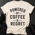 Cream t-shirt with black text "POWERED BY COFFEE & REGRET"