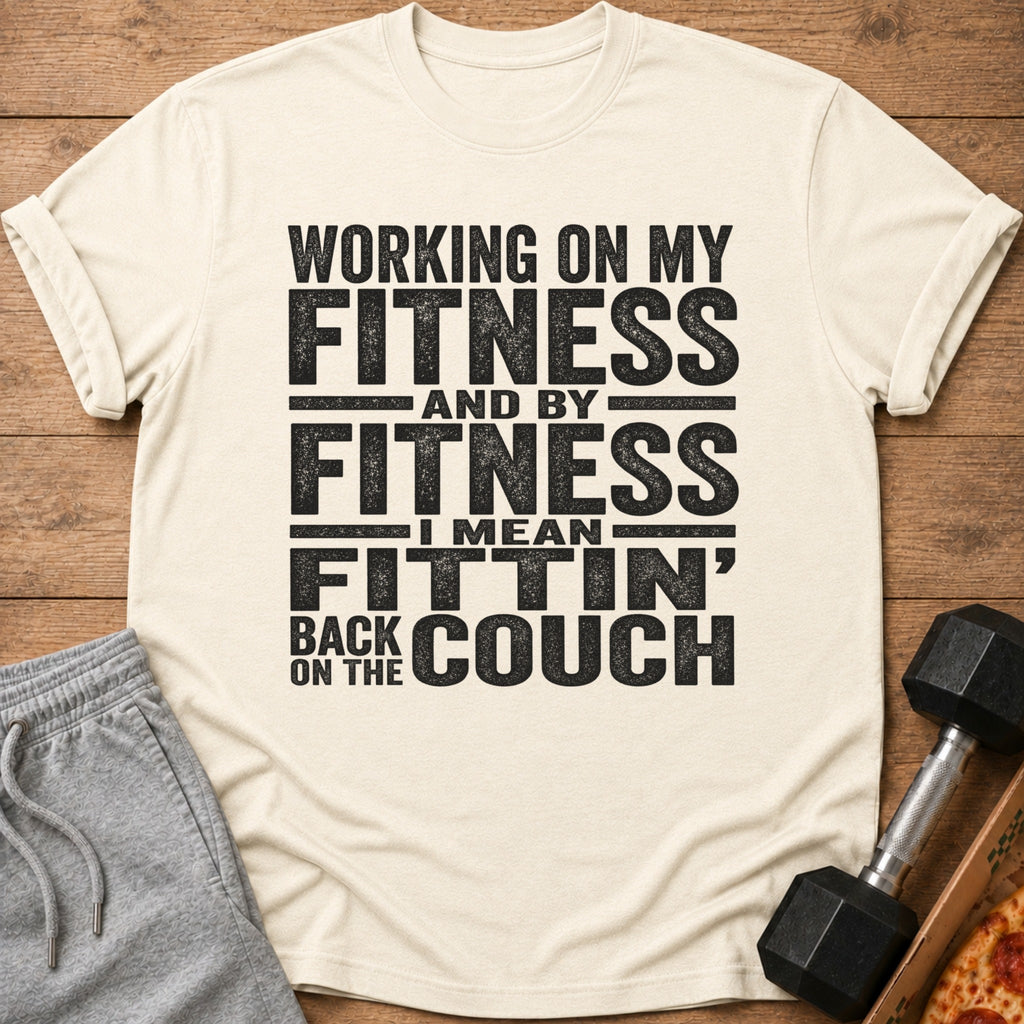 Cream t-shirt with "Working on my fitness and by fitness I mean fittin' back on the couch" text.