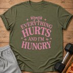 Olive green t-shirt with pink text: "EVERYTHING HURTS AND I'M HUNGRY"