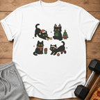 White t-shirt with four cartoon black cats in Christmas-themed poses with a tree.
