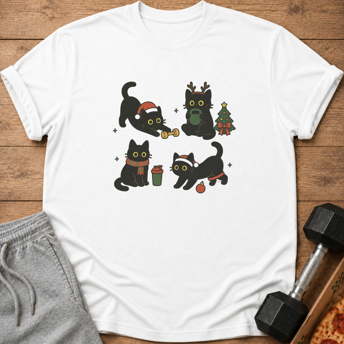 White t-shirt with four cartoon black cats in Christmas-themed poses with a tree.