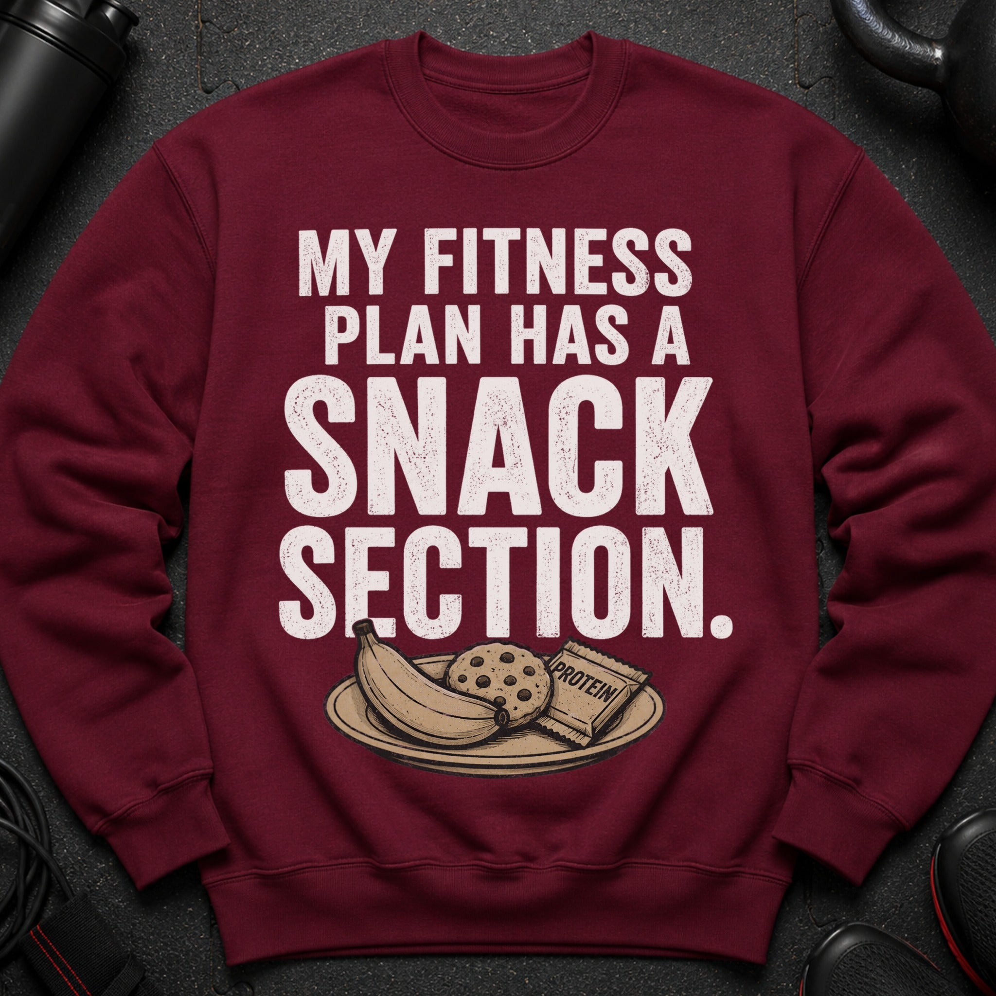 Maroon sweatshirt with text "MY FITNESS PLAN HAS A SNACK SECTION" and image of snacks.