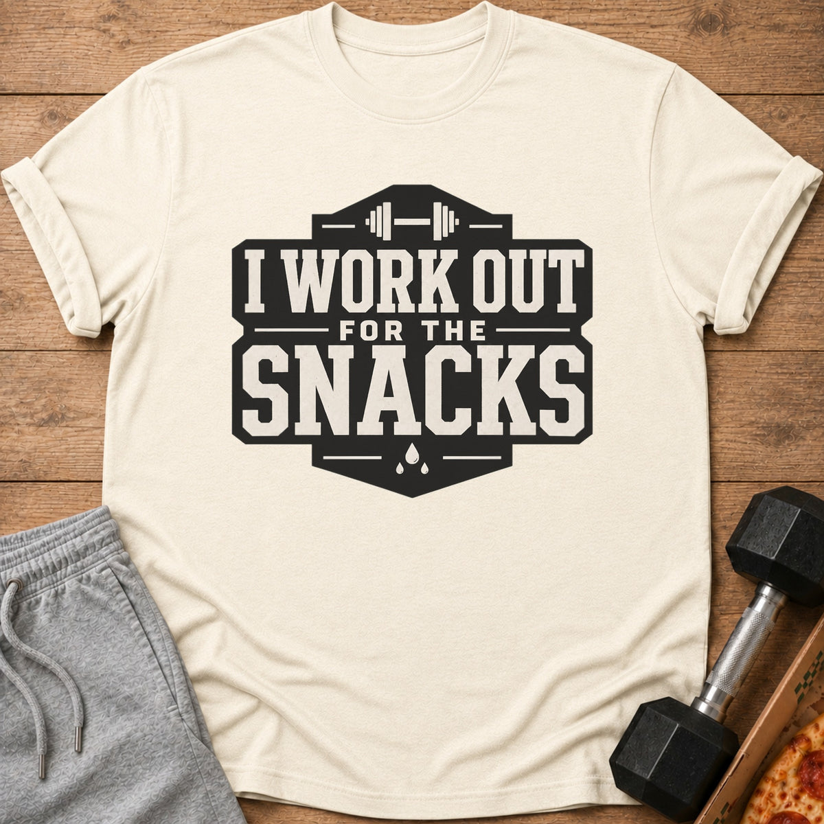 Cream t-shirt with black text "I WORK OUT FOR THE SNACKS" and barbell graphic.