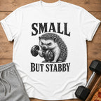 White t-shirt with a graphic of a hedgehog lifting a dumbbell and the text "SMALL BUT STABBY."